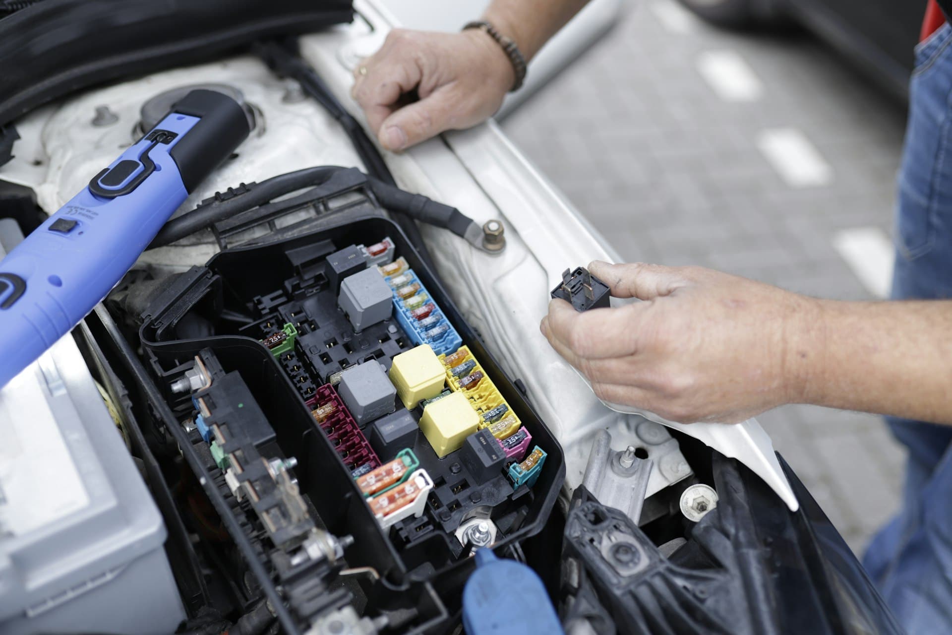 Technician testing relays in an under-bonnet fuse box