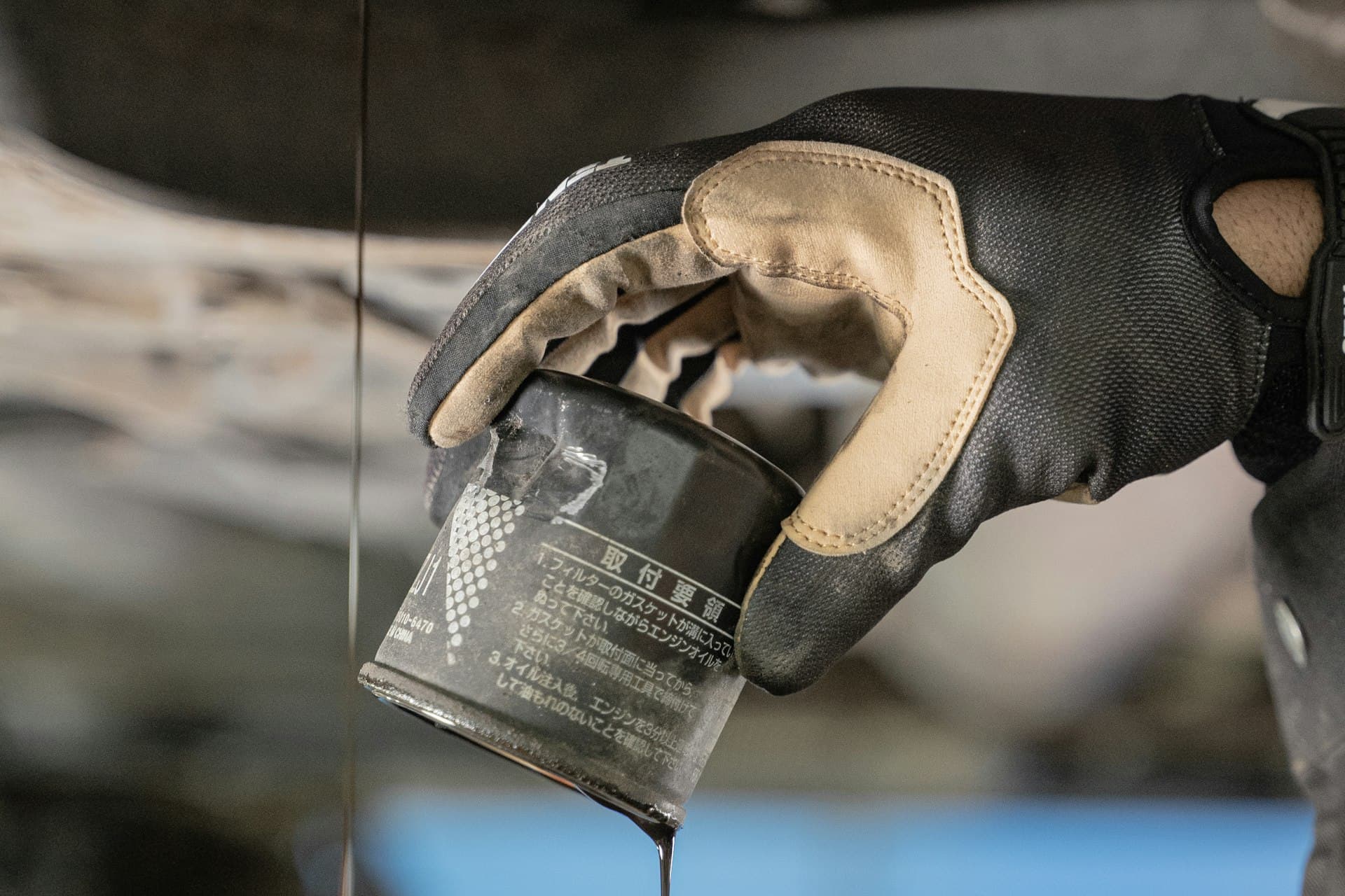 Gloved hand draining a used oil filter