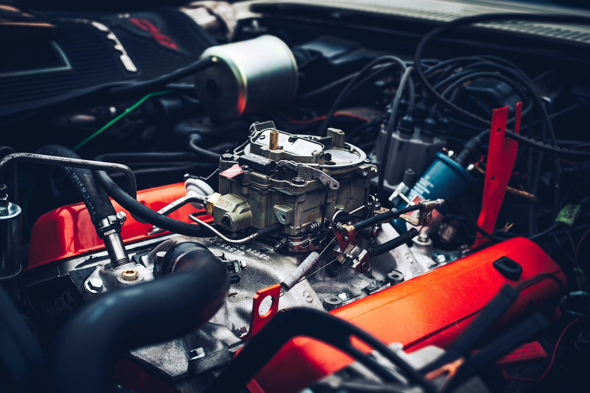 V8 engine bay with red rocker covers and a four-barrel carburettor