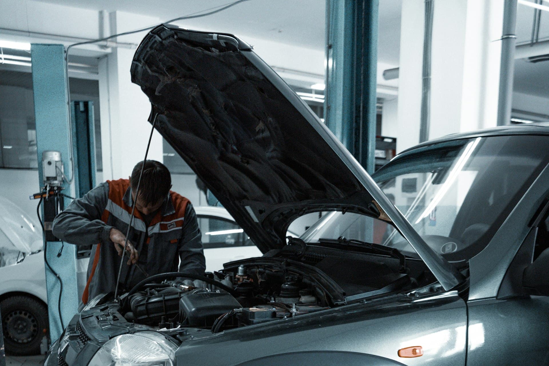 Technician inspecting the engine bay of a car in a workshop